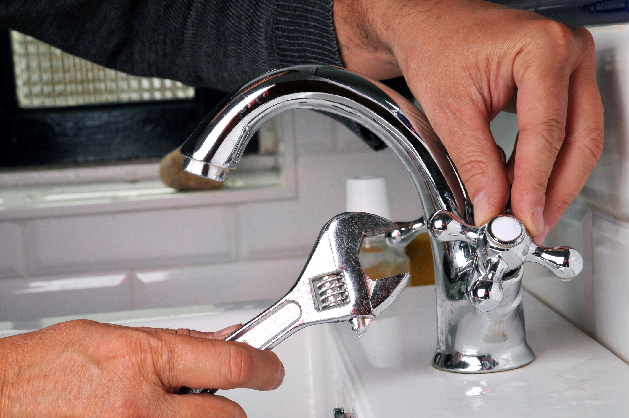 plumber with wrench working on faucet